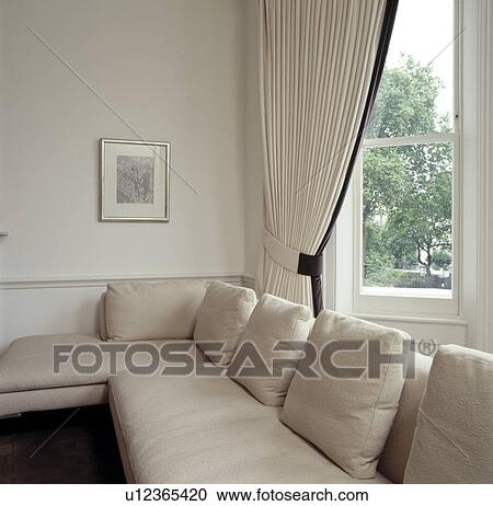 Stock Image - Cream sofa and cream curtains in contemporary living room. Fotosearch