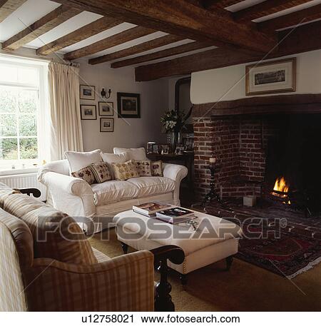 Stock Image - Cream sofa in traditional cottage living room. Fotosearch
