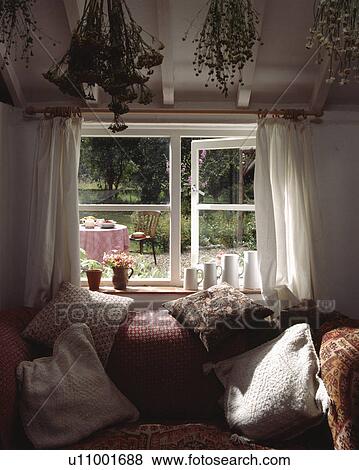 Stock Photo - Cushions on sofa in front of cottage window. Fotosearch