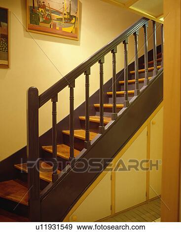 Dark grey bannisters and wooden staircase in pastel yellow hall View Large Photo Image Stock Photo - Dark grey bannisters and wooden staircase in pastel yellow hall. Fotosearch