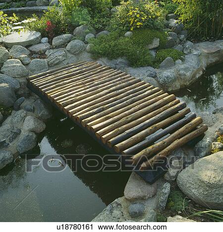 Stock Image - Decking bridge over narrow pond. Fotosearch