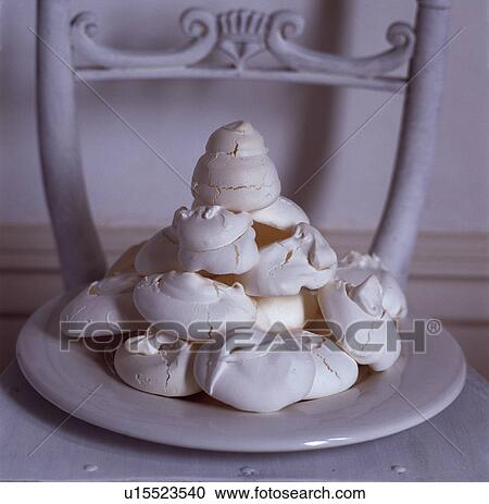 Stock Image - Detail shot of a plate of meringues on a white painted chair. Fotosearch