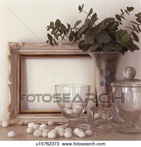 Detail, white picture frame, glass jars and vase with pebbles against a white wall View Large Photo Image Stock Image - Detail, white picture frame, glass jars and vase with pebbles against a white wall . Fotosearch