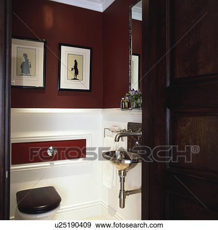 Stock Photo - Door open to dark red and white cloakroom with modern stainless steel basin and tap. Fotosearch
