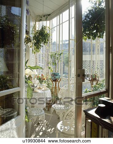 Door open to white metal chairs and table in traditional conservatory extension View Large Photo Image Picture - Door open to white metal chairs and table in traditional conservatory extension. Fotosearch