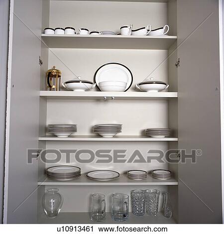Doors open onto white crockery on white shelves in concealed alcove cupboard View Large Photo Image Stock Image - Doors open onto white crockery on white shelves in concealed alcove cupboard. Fotosearch