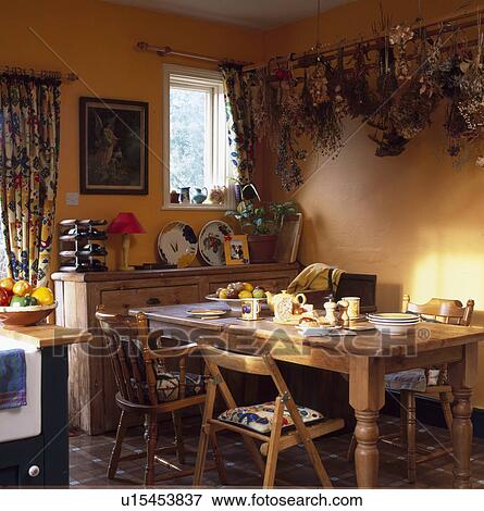 Dried flowers on rack above pine table and chairs in terracotta kitchen View Large Photo Image Stock Photo - Dried flowers on rack above pine table and chairs in terracotta kitchen. Fotosearch