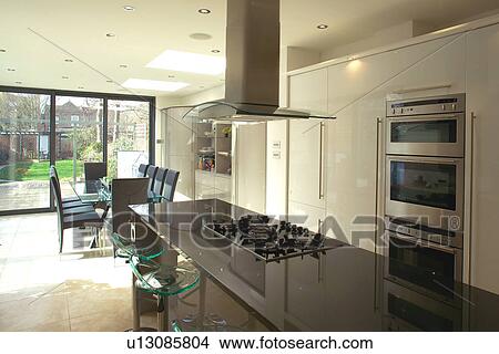 Extractor above hob set into island unit with granite worktop in modern white openplan kitchen and dining room View Large Photo Image Picture - Extractor above hob set into island unit with granite worktop in modern white openplan kitchen and dining room. Fotosearch