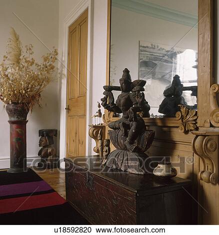Far Eastern sculpture on wooden chest in hall with large mirror View Large Photo Image Stock Image - Far Eastern sculpture on wooden chest in hall with large mirror. Fotosearch