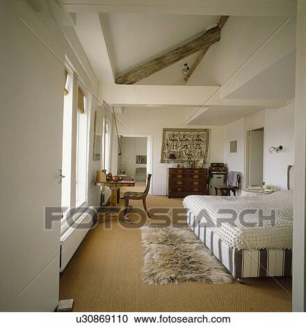Faux fur rug on sisal carpet in modern bedroom in loft conversion View Large Photo Image Stock Image - Faux fur rug on sisal carpet in modern bedroom in loft conversion. Fotosearch