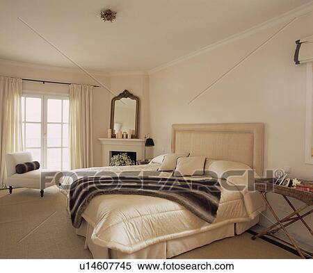 Faux fur throw on bed with cream quilt and upholstered headboard in modern bedroom with beige carpet View Large Photo Image Stock Photography - Faux fur throw on bed with cream quilt and upholstered headboard in modern bedroom with beige carpet. Fotosearch