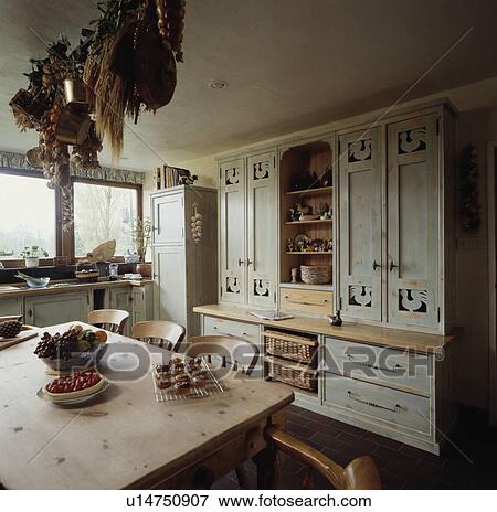 Stock Photo - Fitted painted grey dresser in country kitchen with old pine table and chairs. Fotosearch