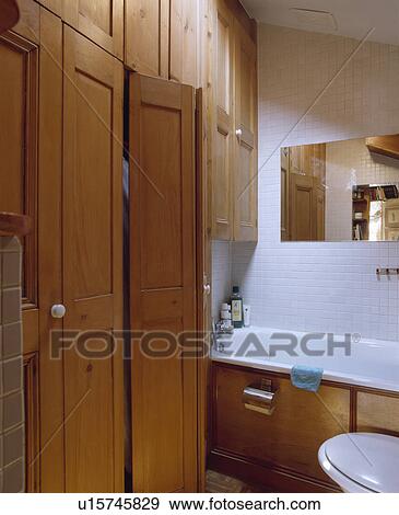 Fitted pine storage cupboards in small white tiled bathroom View Large Photo Image Stock Photo - Fitted pine storage cupboards in small white tiled bathroom. Fotosearch