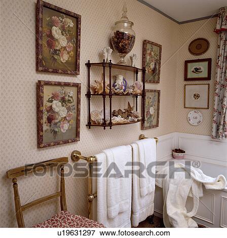 Floral pictures on either side of 3-tier Victorian wall shelf in traditional bathroom with towels on brass towel rail View Large Photo Image Stock Photo - Floral pictures on either side of 3-tier Victorian wall shelf in traditional bathroom with towels on brass towel rail. Fotosearch