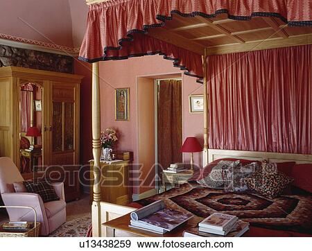Stock Photo - Four-poster bed with pink canopy and drapes in pink townhouse bedroom. Fotosearch
