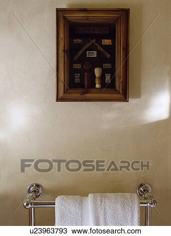 Stock Image - Framed collage of shaving materials above chrome towel rail. Fotosearch