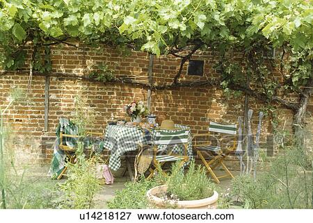 Stock Photo - Furniture on patio in country garden in summer. Fotosearch