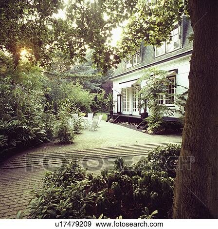 Stock Photo -  Furniture on patio in summer garden in front of country house. Fotosearch