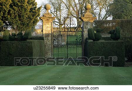 Stock Photo - Gates and stone gateposts with clipped hedges in large country garden. Fotosearch