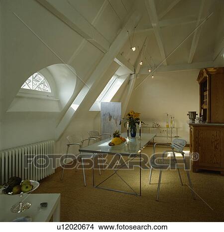 Glass and metal table and metal chairs in white loft conversion dining room with neutral carpet View Large Photo Image Picture - Glass and metal table and metal chairs in white loft conversion dining room with neutral carpet. Fotosearch