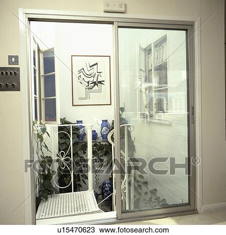 Glass patio doors onto metal staircase in inner atrium with picture above houseplants View Large Photo Image Stock Image - Glass patio doors onto metal staircase in inner atrium with picture above houseplants. Fotosearch