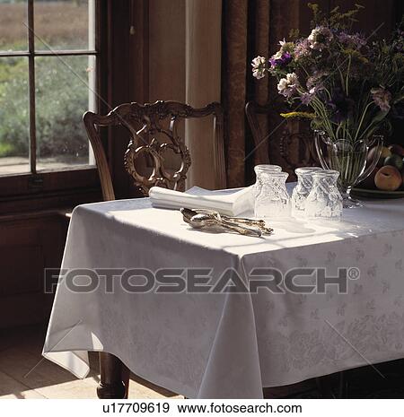 Stock Photo - Glasses and cutlery on white tablecloth in traditional dining room. Fotosearch
