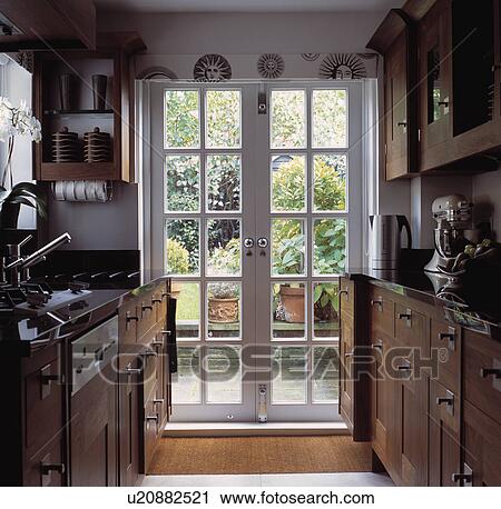 Glazed French doors in traditional galley kitchen with wooden fitted cupbaords View Large Photo Image Stock Image - Glazed French doors in traditional galley kitchen with wooden fitted cupbaords. Fotosearch