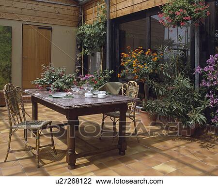 Glazed over area outside house with flowering plants and table & chairs. View Large Photo Image Stock Image - Glazed over area outside house with flowering plants and table & chairs.. Fotosearch