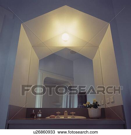 Stock Image - Globe light in mirrored alcove above basin. Fotosearch