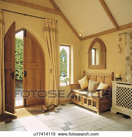 Stock Photography - Gothic wooden double doors in country hall with Gothic mirror above wooden settle. Fotosearch