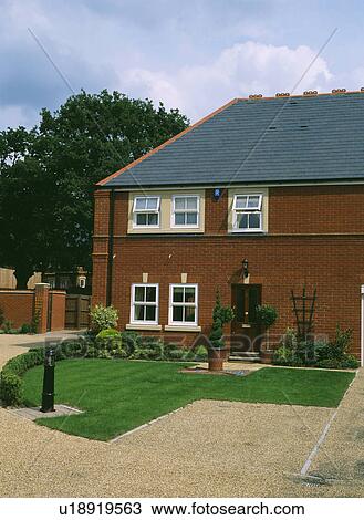 Stock Image - Gravel drive and mown lawn in front of newbuild traditional house. Fotosearch