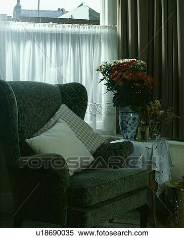 Stock Photography - Green armchair in front of window with net curtains. Fotosearch