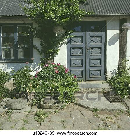 Stock Photo - Grey carved wooden double doors on traditional white single-storey country cottage. Fotosearch