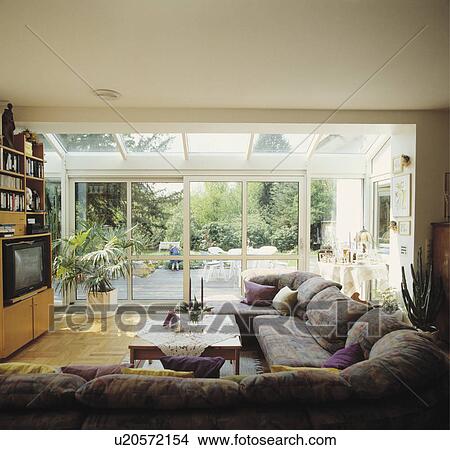 Picture - Grey sofa in modern living room with glass extensions. Fotosearch