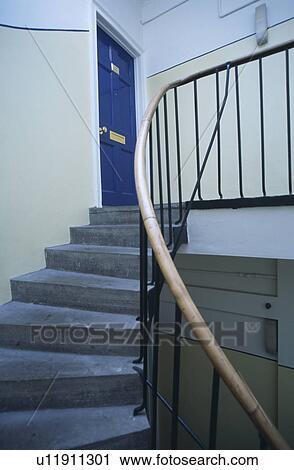 Stock Image - Grey stone staircase to apartment landing with blue door. Fotosearch
