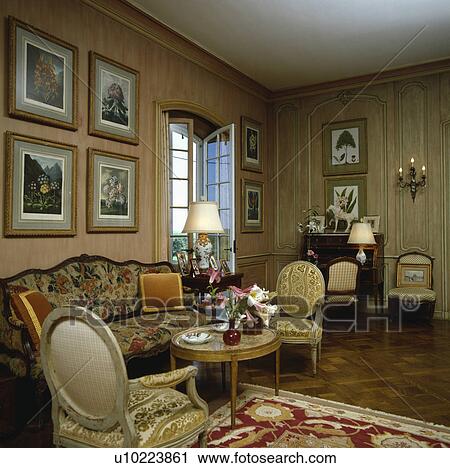 Stock Image - Group of pictures on wall in traditional panelled living room. Fotosearch