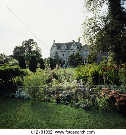 Stock Image - herbaceous borders in garden of large country house. Fotosearch