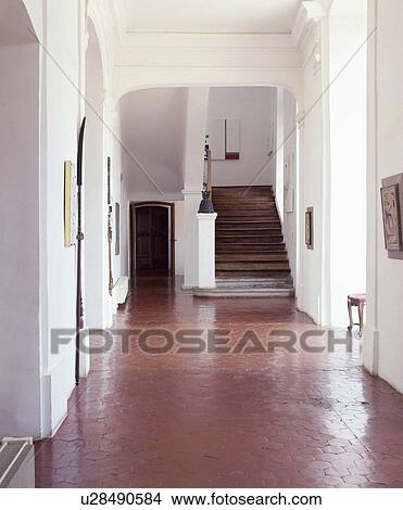 Picture - Hexagonal terracotta tiles on floor in white country hall with wooden staircase. Fotosearch