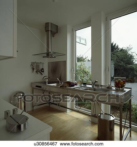 Hob and sink built into freestanding unit in front of tall windows in modern white kitchen View Large Photo Image Stock Photo - Hob and sink built into freestanding unit in front of tall windows in modern white kitchen. Fotosearch