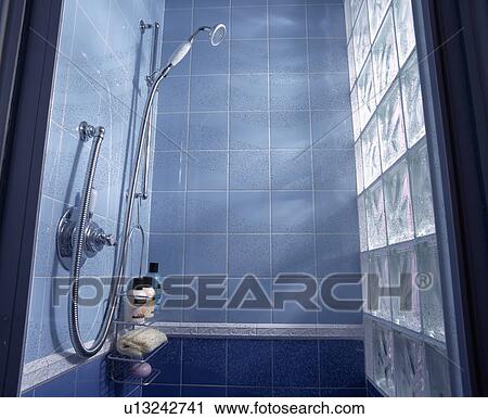 Stock Image - Inside pale blue tiled shower cubicle with glass brick wall. Fotosearch