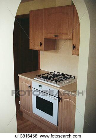 Stock Photo - Kitchen with view through arch to built-in hob and oven. Fotosearch