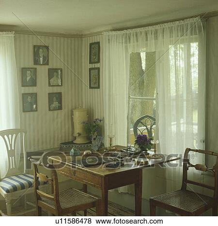 Lace curtains in Scandinavian study with striped wallpaper and antique furniture and photographs on the wall View Large Photo Image Stock Photo - Lace curtains in Scandinavian study with striped wallpaper and antique furniture and photographs on the wall. Fotosearch