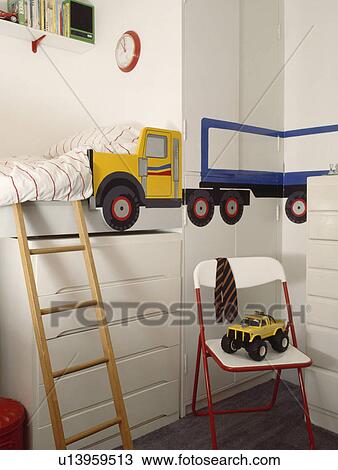 Stock Image - Ladder to bunk bed above storage drawers in boy's bedroom with painted mural of lorry on the wall. Fotosearch