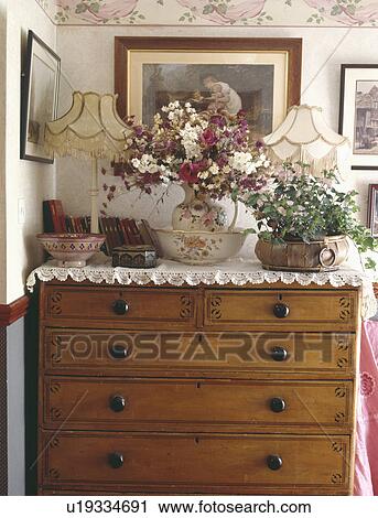 Lamps with fresh flowers and houseplant on antique chest of drawers with lace cloth View Large Photo Image Stock Image - Lamps with fresh flowers and houseplant on antique chest of drawers with lace cloth. Fotosearch