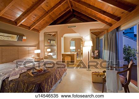 Large bed in modern bedroom with timbered roof and ensuite bathroom View Large Photo Image Stock Photography - Large bed in modern bedroom with timbered roof and ensuite bathroom. Fotosearch