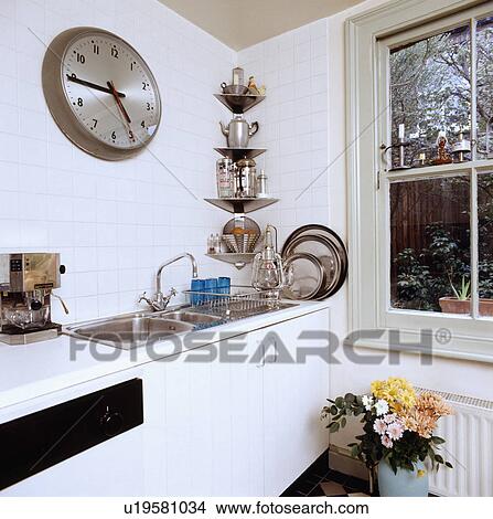 Large clock above double stainless steel sink in white kitchen with stainless steel corner shelves View Large Photo Image Picture - Large clock above double stainless steel sink in white kitchen with stainless steel corner shelves. Fotosearch