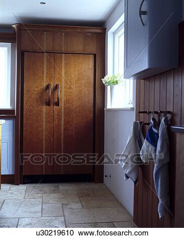 Large fridge-freezer concealed behind inlaid walnut doors in modern kitchen with travertine floor tiles View Large Photo Image Stock Image - Large fridge-freezer concealed behind inlaid walnut doors in modern kitchen with travertine floor tiles. Fotosearch