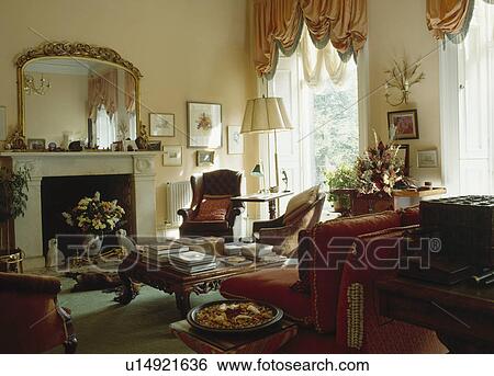 Large gilt mirror above marble fireplace in townhouse living room with peach silk festoon blind View Large Photo Image Stock Photograph - Large gilt mirror above marble fireplace in townhouse living room with peach silk festoon blind. Fotosearch