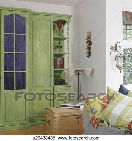 Large green distressed paint effect cupboard in living room with wooden chest & patterned cushions on sofa View Large Photo Image Stock Photography - Large green distressed paint effect cupboard in living room with wooden chest & patterned cushions on sofa. Fotosearch