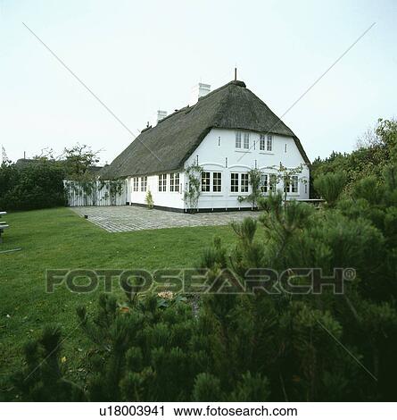 Stock Image - Large lawn in front of traditional white thatched cottage. Fotosearch